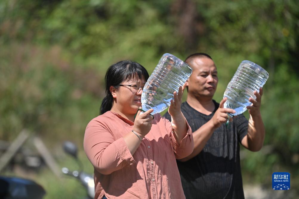 楊寧（左）在查看村民剛剛采集的水樣，為山泉水引水工程做準備（10月8日攝）。新華社記者 黃孝邦 攝